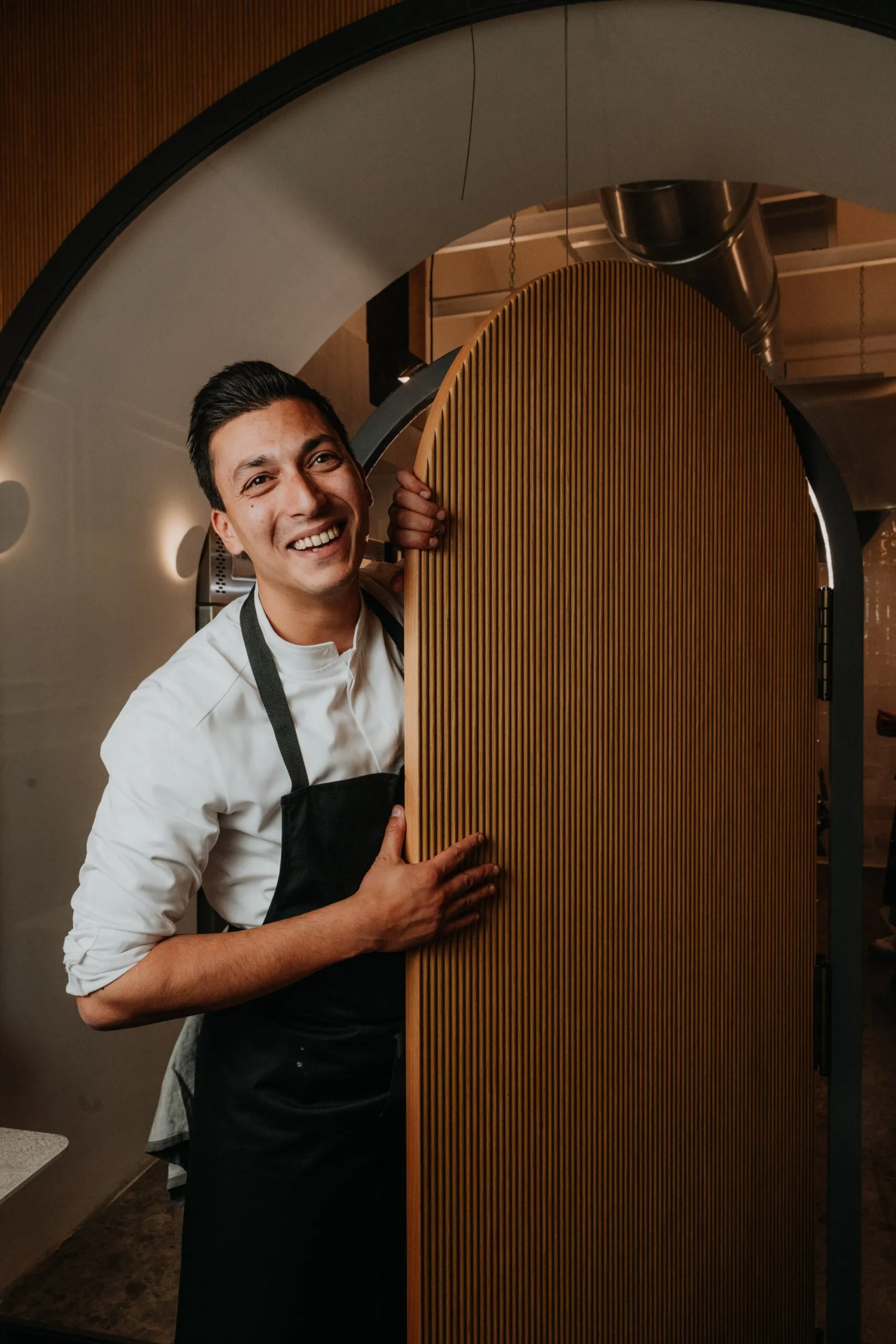 Lo Chef Riccardo Russo alla porta ad arco della cucina a vista